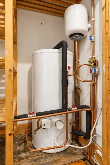 Hot water cylinder and expansion vessel with copper pipework and valves in a domestic heating system.