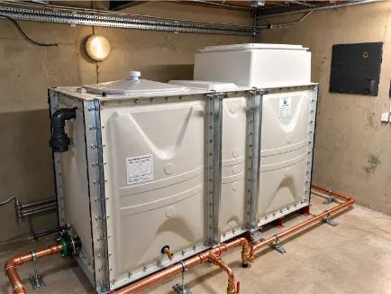 Large modular water storage tank with copper pipework in an indoor utility room