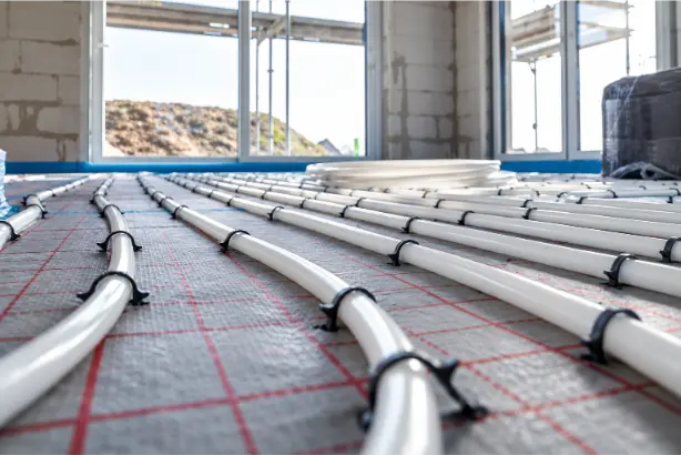 Underfloor heating installation with white heating pipes secured to an insulated subfloor in a new-build property.
